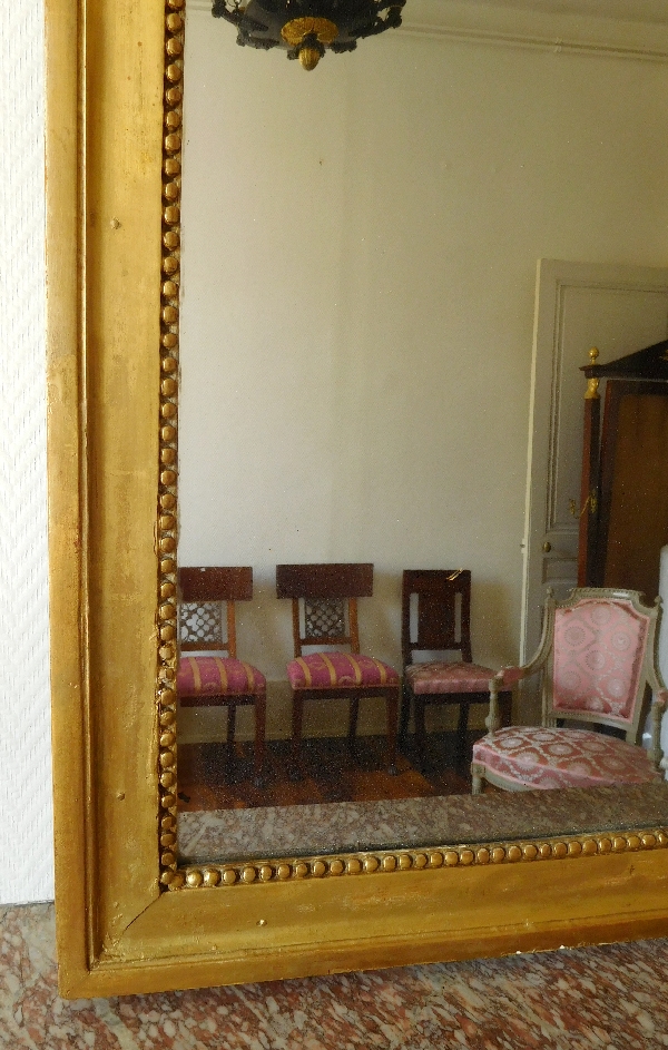 Miroir d'entre deux ou trumeau d'époque Louis XVI, bois doré à la feuille d'or, glace au mercure