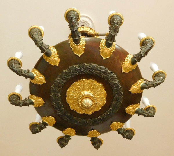 Grand lustre Empire à 12 feux aux barbus en bronze doré et patiné, époque début XIXe