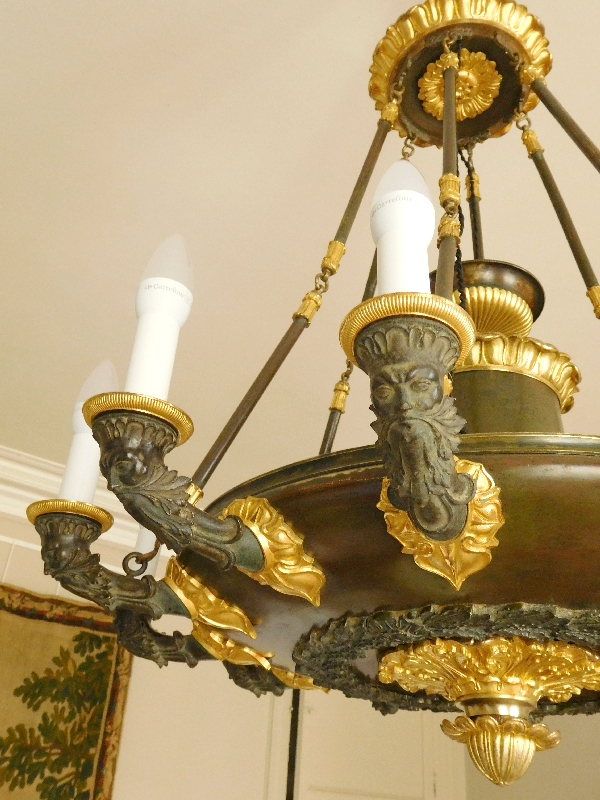 Grand lustre Empire à 12 feux aux barbus en bronze doré et patiné, époque début XIXe