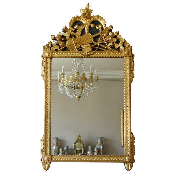 Grand miroir en bois doré d'époque Louis XVI, modèle provençal, fronton à trophée de musique