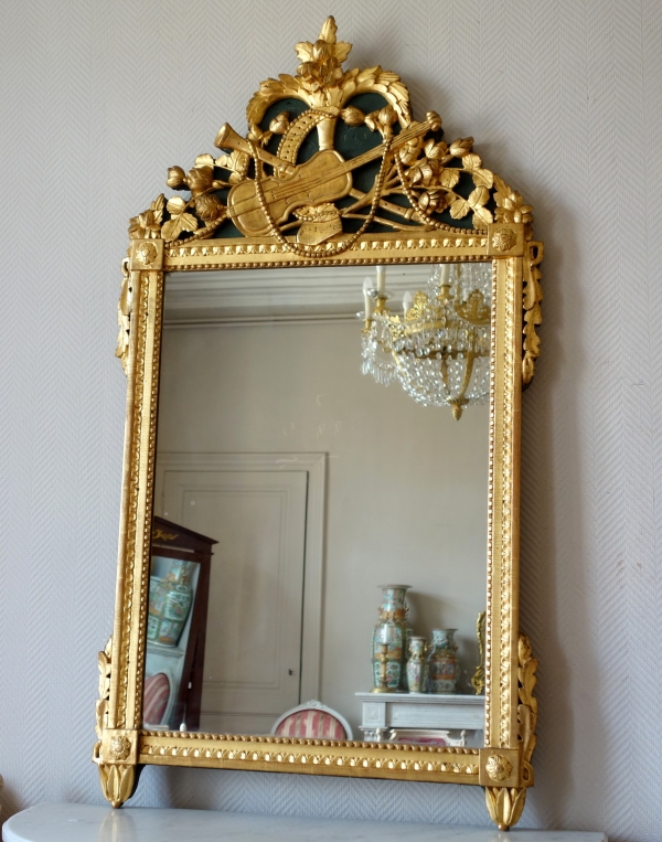 Grand miroir en bois doré d'époque Louis XVI, modèle provençal, fronton à trophée de musique