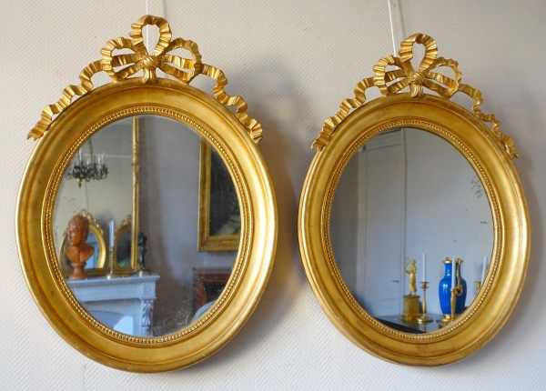 Paire de grands miroirs ovales en bois doré et glace au mercure de style Louis XVI