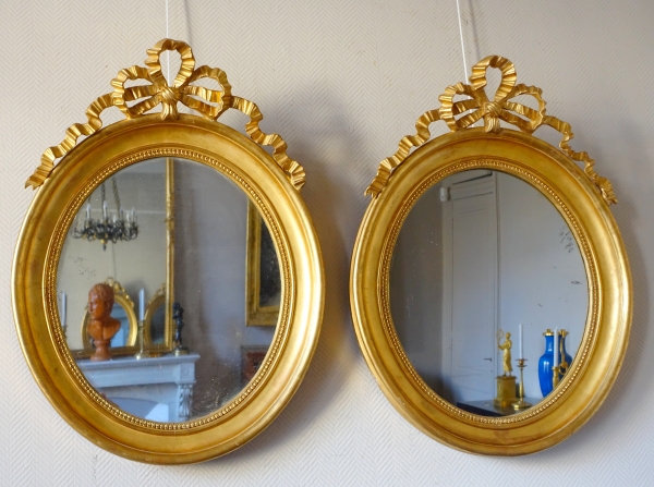 Paire de grands miroirs ovales en bois doré et glace au mercure de style Louis XVI