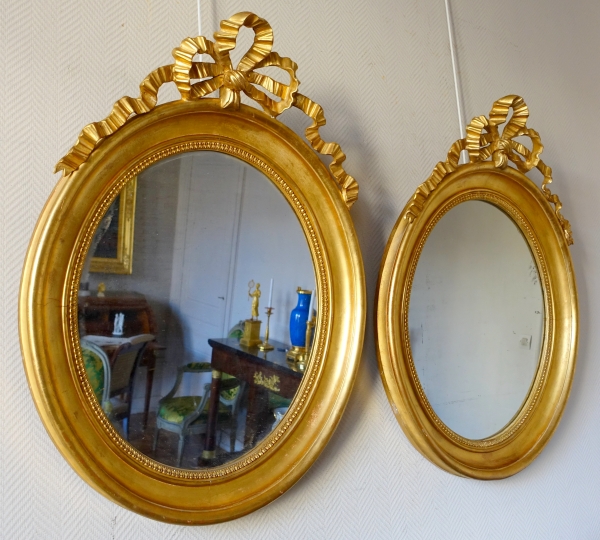 Pair of Louis XVI style gold leaf gilt wood oval mirrors, 19th century