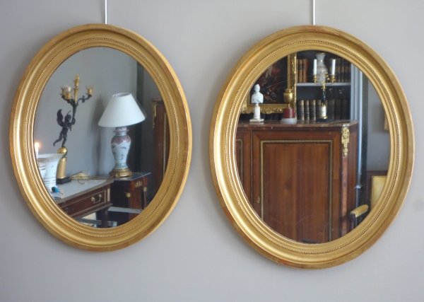 Paire de grands miroirs ovales en bois doré, glace au mercure - style Louis XVI