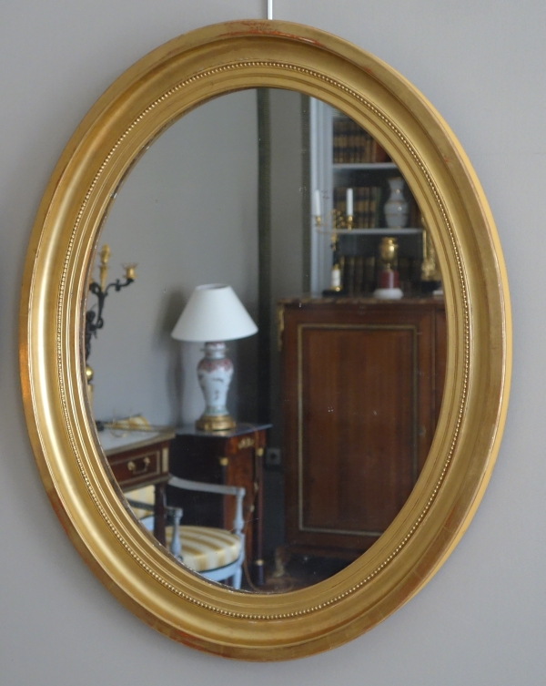 Paire de grands miroirs ovales en bois doré, glace au mercure - style Louis XVI